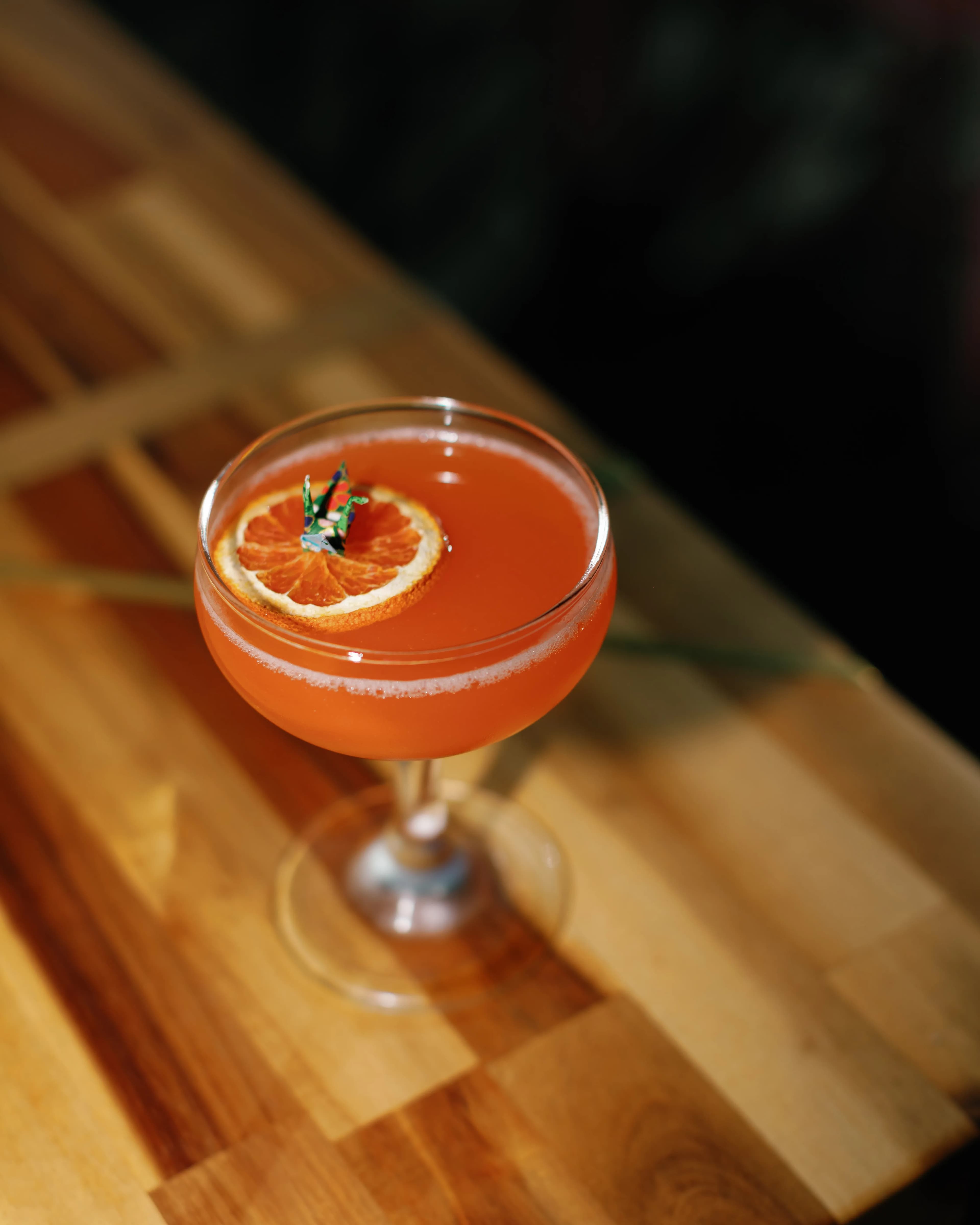 Paper Plane cocktail in a coupe glass with marigold and orange garnish at Darling Aviary rooftop cocktail bar in Downtown Sacramento