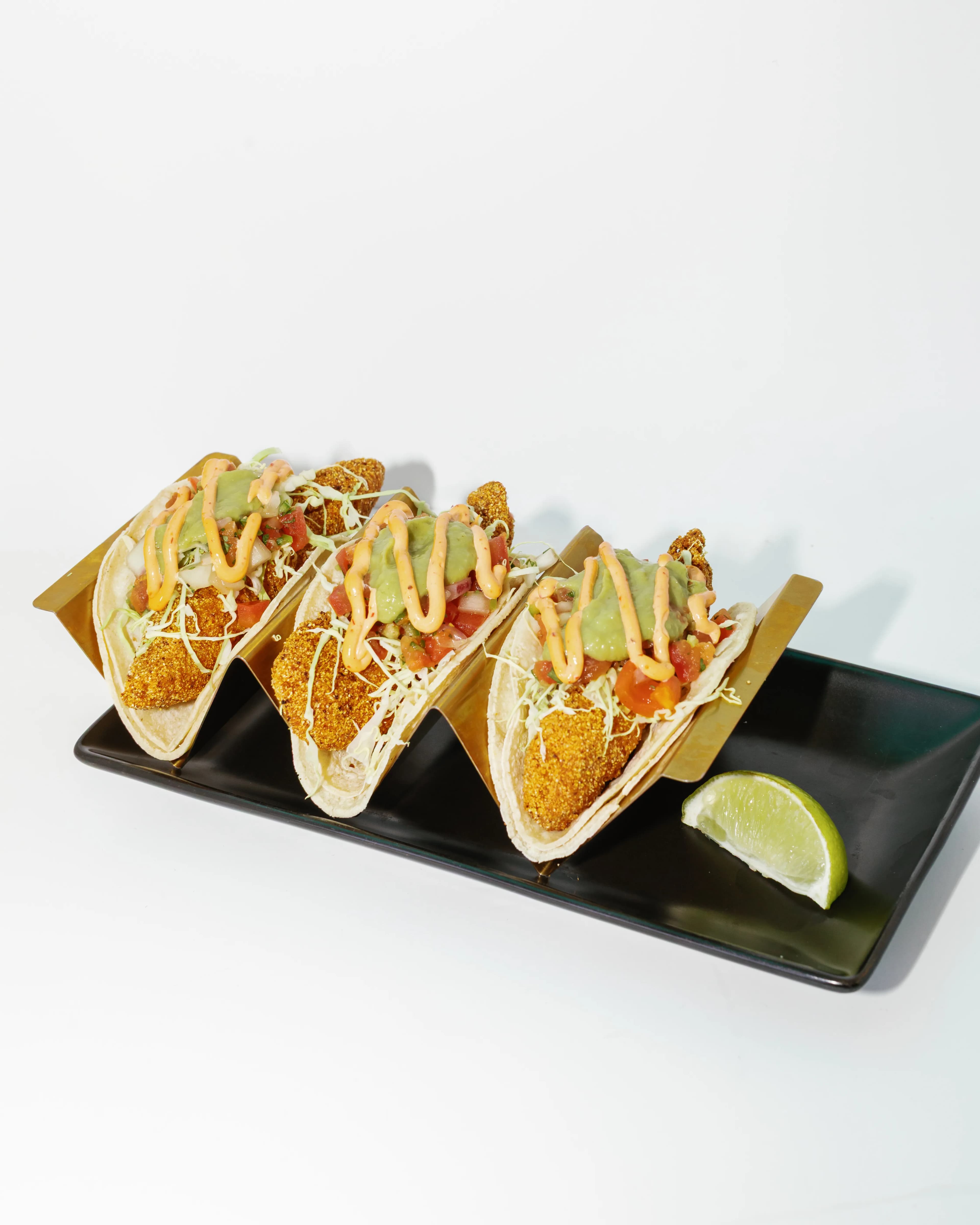 Darling Aviary crispy fish tacos in flour tortillas with avocado crema, chipotle drizzle and shredded cheese, served with a lime wedge at rooftop restaurant in DoCo, Downtown Sacramento